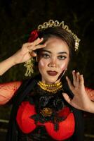 An Indonesian dancer in red clothes and a black scarf poses with very curly and beautiful fingers photo