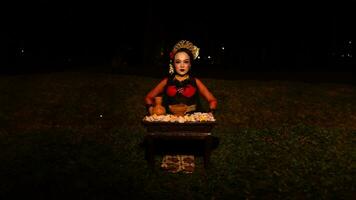 a female dancer looks focused on her ritual with a peaceful facial expression in front of offerings that look fresh and lively photo