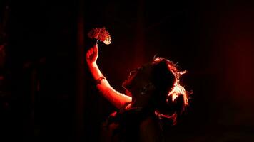 the silhouette of a female dancer holding jewelry that looks like a reflection reflecting in the dim light photo