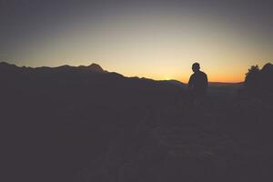 Hiker on a mountain top at sunset. Woman admiring mountain landscape in High Tatra Mountains, Poland. photo