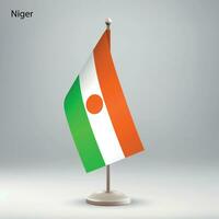 Flag of Niger hanging on a flag stand. vector