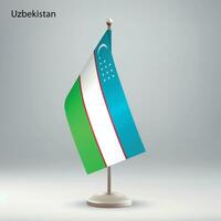 Flag of Uzbekistan hanging on a flag stand. vector