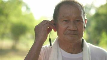 senior mensen slijtage hoofdtelefoons naar oefening in de park. video
