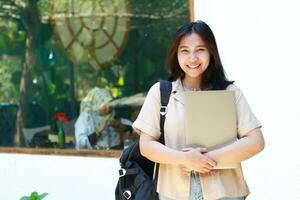 smiling asian woman standing in front of cafe bring laptop and backpack wearing stylish casual clothes, female small business owner photo