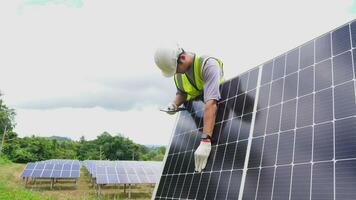 asiático hombre ingeniero utilizando digital tableta mantener solar célula paneles trabajando al aire libre en ecológico solar granja construcción. foto