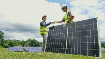 dos asiático ingenieros sacudida manos después instalando solar paneles . solar energía limpiar y verde alternativa energía. unidad y trabajo en equipo. foto