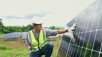 asiático hombre ingeniero utilizando digital tableta mantener solar célula paneles trabajando al aire libre en ecológico solar granja construcción. foto