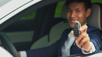 Young asian businessman showing a car key inside his new electric vehicle. EV Car. photo