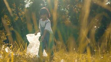 Kid Girl  collection plastic garbage in nature. kid picking up trash in park. photo