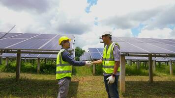 dos asiático ingenieros sacudida manos después instalando solar paneles . solar energía limpiar y verde alternativa energía. unidad y trabajo en equipo. foto