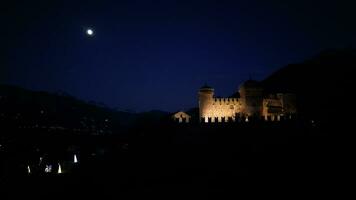 Night aerial view of Fenis castle with full moon Aosta Valley Italy video
