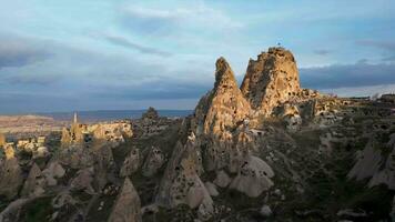 aéreo zumbido ver de el uchisar castillo en capadocia, Turquía durante puesta de sol. esta alto Roca volcanica afloramiento es uno de de capadocia más prominente puntos de referencia video