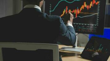 Businessman analyzing a graphic of a stock exchange chart. Back of the head of a young male businessman looking at a stock diagram on the big screen of the computer video