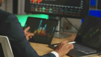 Businessman analyzing a graphic of a stock exchange chart. Back of the head of a young male businessman looking at a stock diagram on the big screen of the computer video