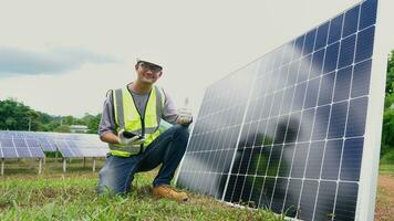 asiático hombre ingeniero utilizando digital tableta mantener solar célula paneles trabajando al aire libre en ecológico solar granja construcción. foto