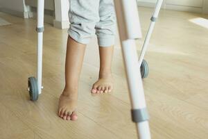 child with walking frame and knee orthosis indoor photo