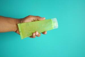 holding a plastic container of aloe vera liquid gel photo