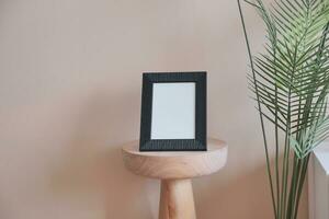 empty photo frame on table against white light orange color wall