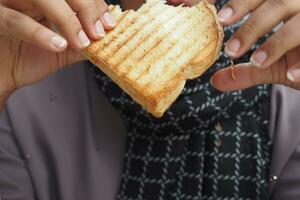 mujer comiendo tostado emparedado con jamón y queso, foto
