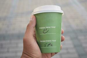 holding a take away kraft coffee cup with happy new year wish on it photo