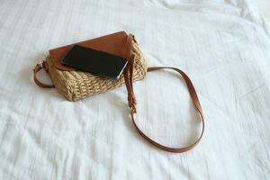women purse wallet and a smart phone on bed, close up. photo