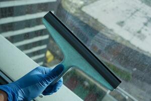 person hand in gloves cleaning window glass photo