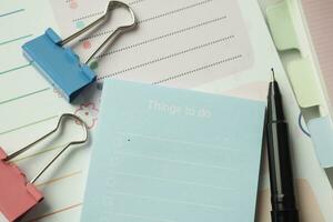 lista de tareas en el cuaderno con proveedores de oficina en el escritorio. foto