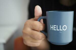 women holding a blue coffee cup with hello word photo