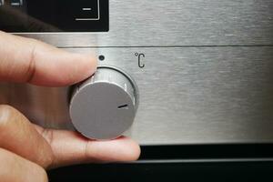 Close up of men hand setting temperature control on oven. photo