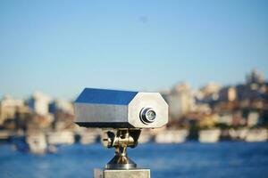 Coin-operated binoculars looking out over city , photo