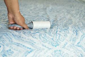 using an adhesive roller to remove lint and fluff from a bed . photo