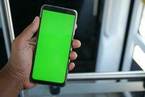 young man hand using smart phone with green screen inside of metro train photo