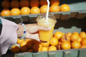 women holding a bottle of orange juice against against fruit background photo