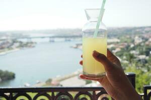 holding a glass of orange juice against blue sky photo