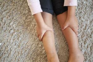 top view of child holding her feet suffering pain photo