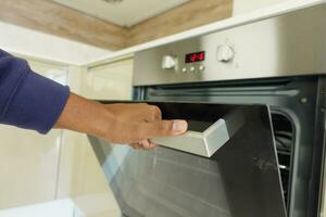 hand holding a door of electric oven at home photo