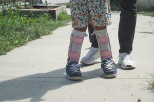 Child cerebral palsy disability with legs orthosis walking outdoor photo