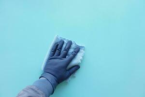 hand in blue rubber gloves cleaning table with cloth photo