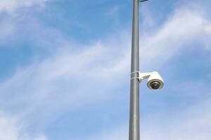 CCTV security camera operating outdoor against blue sky photo