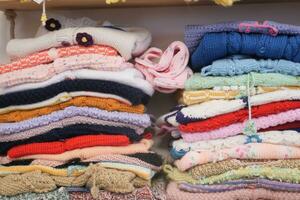 stack of knitted warm sweaters with different knitting pattern in a shelf photo