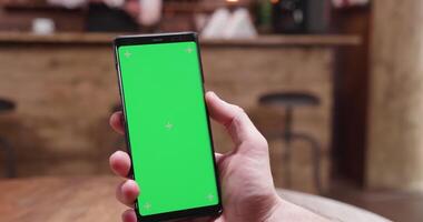 Fast moving parallax shot of phone with green screen on the display in a cozy and hipster establishment video