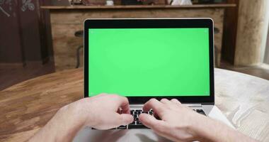 pov tiro do pessoa trabalhando em uma moderno computador portátil com verde tela dentro uma vintage interior video