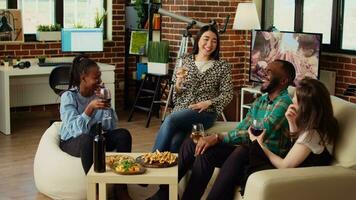 Diverse group friends celebrating asian woman birthday, drinking alcoholic beverages and eating appetizers in living room. Happy guests laughing and discussing after gifting host presents video