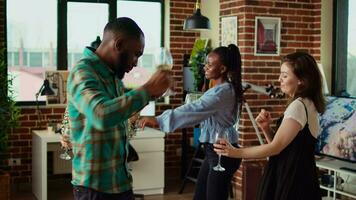 Young adults of various nationalities dancing at home party while drinking alcohol. Friends hanging around, having good time together while enjoying upbeat music in living room video