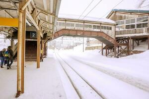 Outside view of Hakodate ancient local train station's buildings and metal long railroad track covered by thick snow in winter season  white foggy background. photo