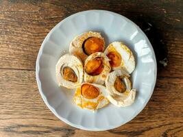 Top view of Chinese salt eggs cut in half and ready to eat on white ceramic plate on wooden table background. photo