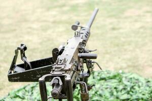 Closeup and back view of M2 .50cal Browning machine gun with tripod standing in bunker and on blurry background. photo