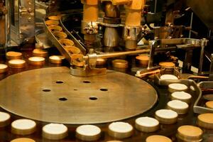 Closeup cheese cakes making machine in the bakery factory making and drop cheese cakes ingredients in molds to prepare baked and sell to customer. photo