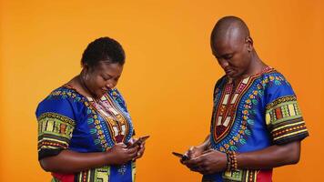 africano americano coppia controllo sociale media Rete su smartphone app, lettura loro messaggi su Internet connessione. uomo e donna utilizzando mobile Telefono per scorrere su siti web. video