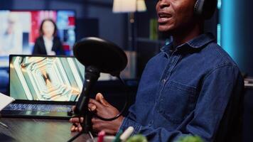 africain américain homme invité à podcast, participant dans divertissant discussion avec hôte dans appartement studio. de bonne humeur client parlant dans professionnel microphone pendant en ligne comédie spectacle video